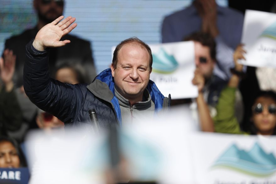 FILE - In this Wednesday, Oct. 24, 2018, file photograph, Jared Polis, Colorado's governor-elect, waves to voters before U.S. Senator Bernie Sanders speaks during a rally with young voters on the campus of the University of Colorado in Boulder, Colo. Polis will take the oath of office Tuesday, Jan. 8, 2019, to become the nation's first, openly-gay governor. (AP Photo/David Zalubowski, File)