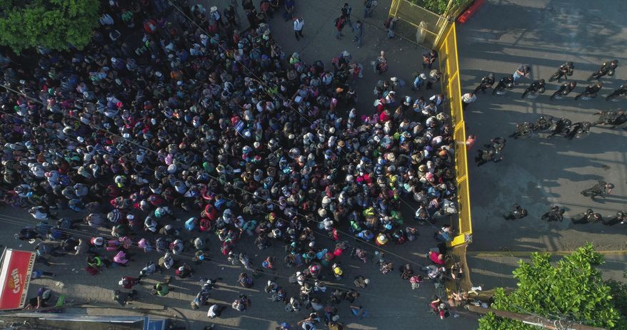 FILE - In this Nov. 2, 2018 file photo, Salvadoran migrants mass on the gate on the Guatemalan side of the Mexico-Guatemala border in Tecun Uman, as they make their way north with the stated purpose of reaching the United States, before they turned around and waded across a shallow stretch of the river to enter Mexico. The Mexican government announced on Jan. 8, 2019 that it will put guards at some 370 illegal crossing points along the country’s southern border with Guatemala. (AP Photo/Oscar Rivera, File)