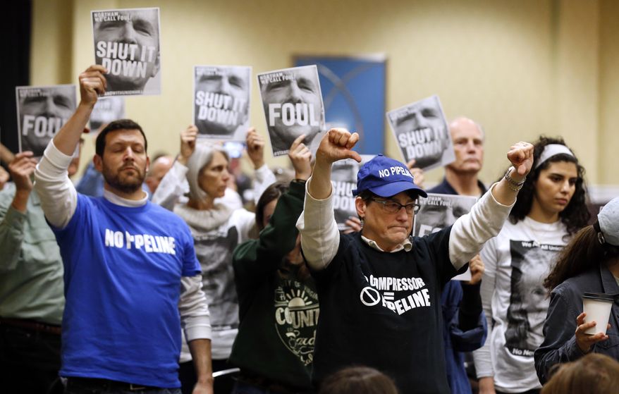 Protesters hold signs as they turn their backs on a meeting of the Virginia State Air Quality Control Board in Richmond, Va., Tuesday, Jan. 8, 2019. The board is set to vote on a plan to build an Atlantic Coast Pipeline Compressor station in the state. (AP Photo/Steve Helber)