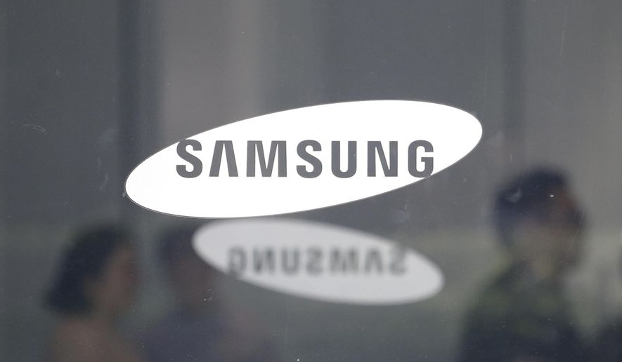 FILE - In this July 31, 2018 file photo, employees walk past logos of the Samsung Electronics Co. at its office in Seoul, South Korea,  Samsung is giving a weak fourth-quarter operating profit forecast, as the smartphone and memory chip maker contends with increased competition and softer chip demand.  The announcement, Monday, Jan. 7, 2019,  follows Apple’s disclosure that its revenue for the last quarter of 2018 will fall well below projections, a decrease the company traced mainly to China. Apple is one of Samsung’s chip customers.  (AP Photo/Ahn Young-joon, File)