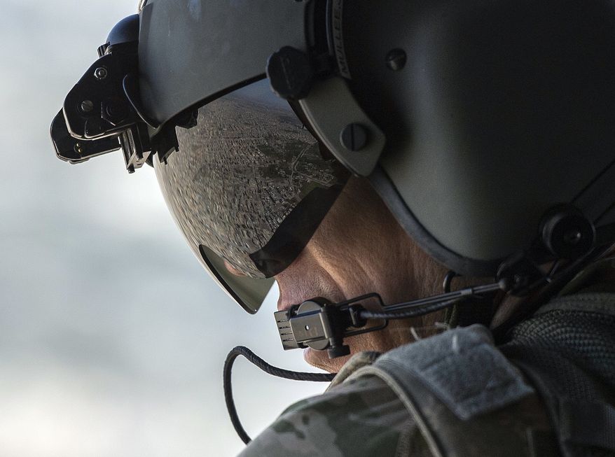 A partial view of Baghdad is reflected in the visor of a U.S. Army helicopter crew member as he looks out of a Chinook helicopter flying from the U.S. Embassy to Baghdad International Airport, following the helicopter of U.S. Secretary of State Mike Pompeo on Wednesday, Jan. 9, 2019. (Andrew Caballero-Reynolds/Pool Photo via AP)