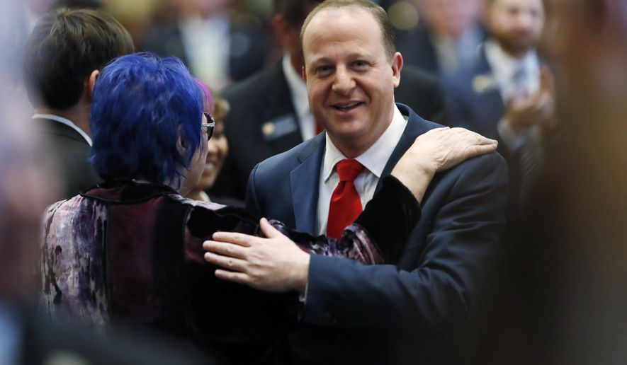 Colorado Gov. Jared Polis, right, greets his mother, Susan Polis Schutz, as he make his way through the House of Representatives to deliver his first State of the State address to a joint session of the Colorado Legislature, Thursday, Jan. 10, 2019, in Denver. (AP Photo/David Zalubowski)