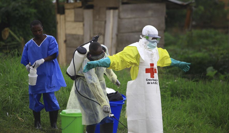 In this Sunday, Sept 9, 2018, photo, a health worker sprays disinfectant on his colleague after working at an Ebola treatment center in Beni, Eastern Congo. (AP Photo/Al-hadji Kudra Maliro) **FILE**