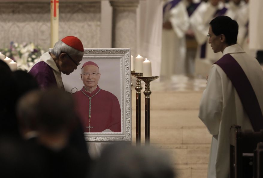 Cardinal Joseph Zen, left, a vocal opponent of attempts by Beijing and the Vatican at rapprochement, walks past the picture of Bishop Michael Yeung as he presides a vigil Mass in Hong Kong, Thursday, Jan. 10, 2019. Hong Kong Catholics mourned the loss of their bishop with a Mass on Thursday night amid a low-key struggle among clergy over reconciliation between the Vatican and Beijing. Bishop Michael Yeung died last week from liver failure after less than two years as the head of the diocese of more than 500,000 Catholics in the semi-autonomous Chinese territory. (AP Photo/Vincent Yu)