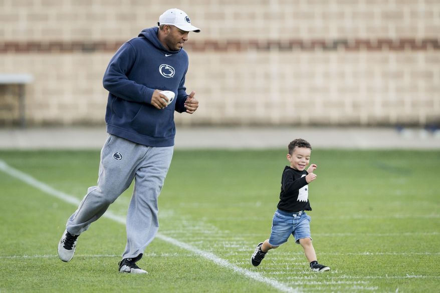 FILE - In this Sept. 27, 2017, file photo, then-Penn State wide receivers coach Josh Gattis chases his son Jace, 2, following NCAA college football practice, in State College, Pa. Michigan hired Josh Gattis away from Alabama to be Jim Harbaugh’s offensive coordinator on Thursday, Jan. 19, 2019. The 34-year-old Gattis was a co-offensive coordinator last season for the Crimson Tide. Gattis was Penn State’s wide receivers coach and passing-game coordinator and led the program’s offensive recruiting efforts the previous four seasons. (Joe Hermitt/The Patriot-News via AP, File)