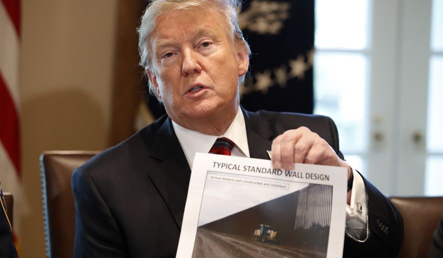 President Donald Trump holds a photo as he leads a roundtable discussion on border security with local leaders, Friday Jan. 11, 2019, in the Cabinet Room of the White House in Washington. (AP Photo/Jacquelyn Martin)