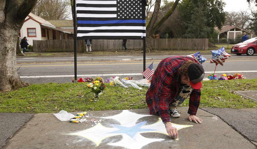Matthew Ottele draws a star on the sidewalk Friday, Jan. 11, 2019, near the scene were Davis Police Officer Natalie Corona was shot and killed in Davis, Calif. Corona, 22, who had been on the job only a few weeks was slain, Thursday, by a suspect who opened fire as she was investigating a three-car crash. The suspect was later found dead from a self-inflicted gunshot, following a standoff with officers. (AP Photo/Rich Pedroncelli)