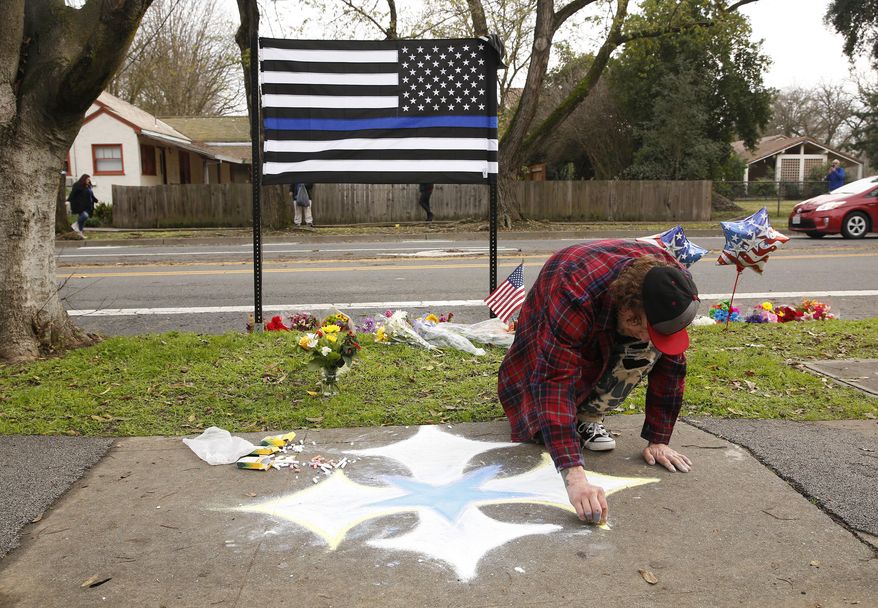 Matthew Ottele draws a star on the sidewalk Friday, Jan. 11, 2019, near the scene were Davis Police Officer Natalie Corona was shot and killed in Davis, Calif. Corona, 22, who had been on the job only a few weeks was slain, Thursday, by a suspect who opened fire as she was investigating a three-car crash. The suspect was later found dead from a self-inflicted gunshot, following a standoff with officers. (AP Photo/Rich Pedroncelli)