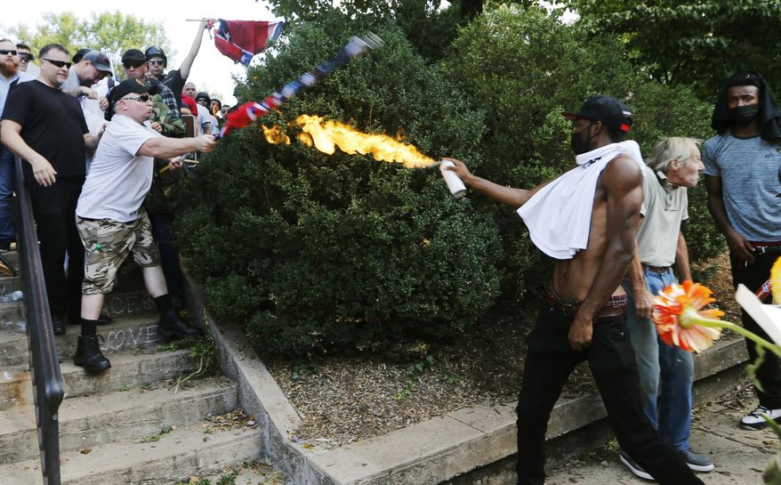 FILE - In this Aug. 12, 2017, file photo, counter demonstrator Corey Long points a lighted aerosol spray towards a white nationalist demonstrator at the entrance to Lee Park in Charlottesville, Va. Long, a black counterprotester is no longer appealing his conviction for using an improvised flamethrower during the 2017 white nationalist rally in Charlottesville. Citing court documents, news outlets report that Long dropped his appeal Jan. 10, two weeks before a hearing in Charlottesville Circuit Court. (AP Photo/Steve Helber, File)