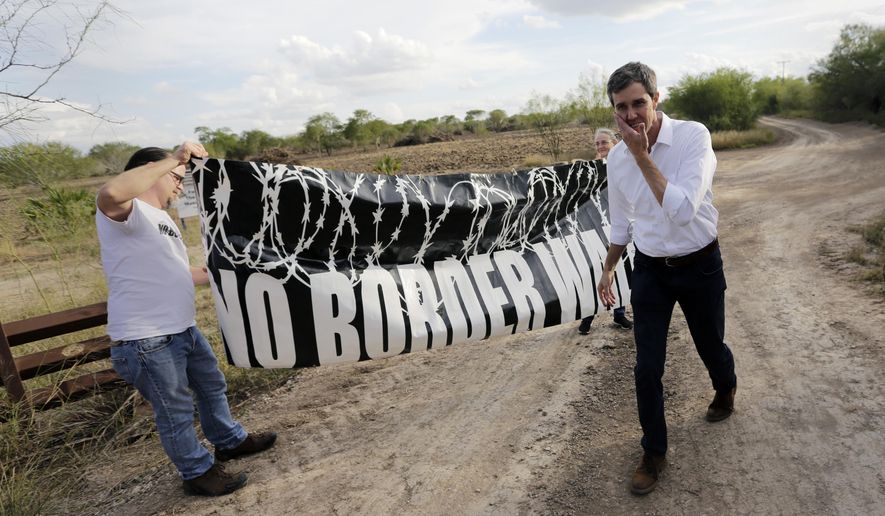 FILE - In this Saturday, Jan. 6, 2018, file photo, Texas Democratic Congressman Beto O'Rourke, right, passes a "No Border Wall" sign during a visit to the National Butterfly Center in Mission, Texas, a possible location for a border wall. President Donald Trump is not giving up on his demands for $5.7 billion to build a wall along the U.S.-Mexico border, saying a physical barrier is central to any strategy for addressing the security and humanitarian crisis at the southern border. Democrats argue that funding the construction of a steel barrier along roughly 234 miles will not solve the problems. (AP Photo/Eric Gay, File) **FILE**