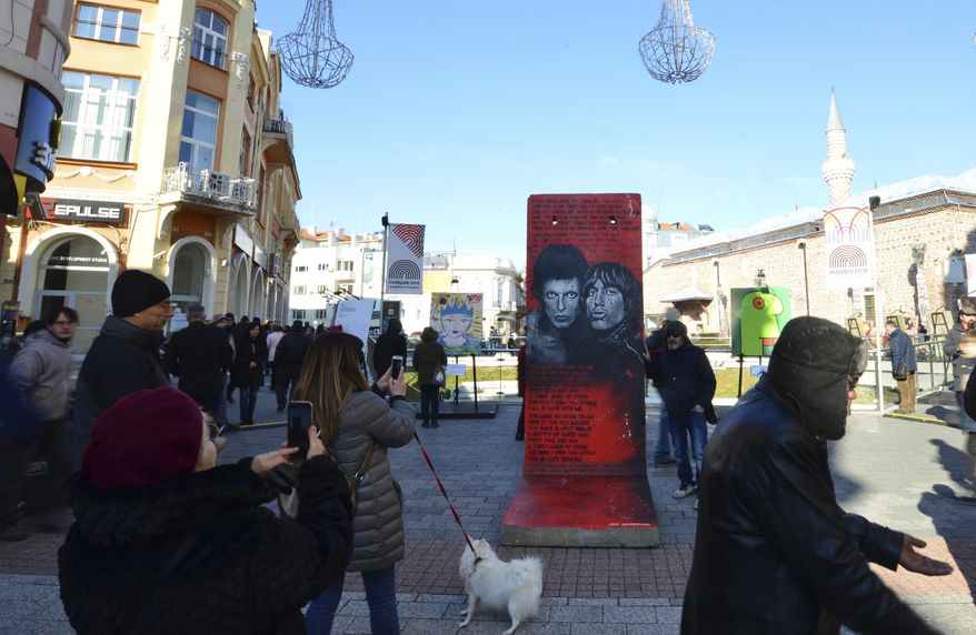 People take pictures of exhibits at the Art Liberte exhibition, the first traveling exhibition to mark the 30 years anniversary of fall of the Berlin wall in the town of Plovdiv ahead of the opening ceremony of Plovdiv as one of European Capital of Culture, Bulgaria, Saturday, Jan. 12, 2019. Plovdiv is the first Bulgarian town named to celebrate the most prestigious cultural initiative of the European Union, along with the Italian city of Matera as the twin European Capital of Culture for 2019. (AP Photo/STR)