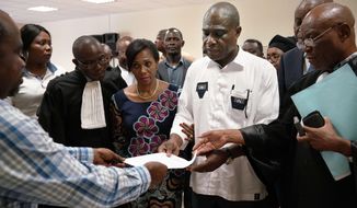 Accompanied by his wife and his lawyers, Congo opposition candidate Martin Fayulu receives the receipt after petitioning the constitutional court following his loss in the presidential elections in Kinshasa, Congo, Saturday Jan. 12, 2019. The ruling coalition of Congo&#39;s outgoing President Joseph Kabila has won a large majority of national assembly seats, the electoral commission announced Saturday, while the presidential election runner-up was poised to file a court challenge alleging fraud. (AP Photo/Jerome Delay)