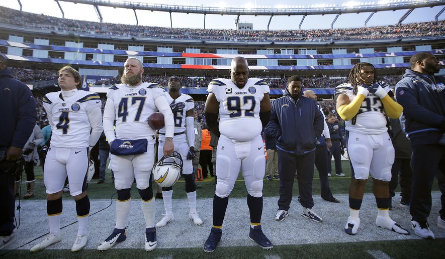 Los Angeles Chargers players, including defensive tackle Brandon Mebane (92), stand during the national anthem before an NFL divisional playoff football game against the New England Patriots, Sunday, Jan. 13, 2019, in Foxborough, Mass. (AP Photo/Steven Senne)