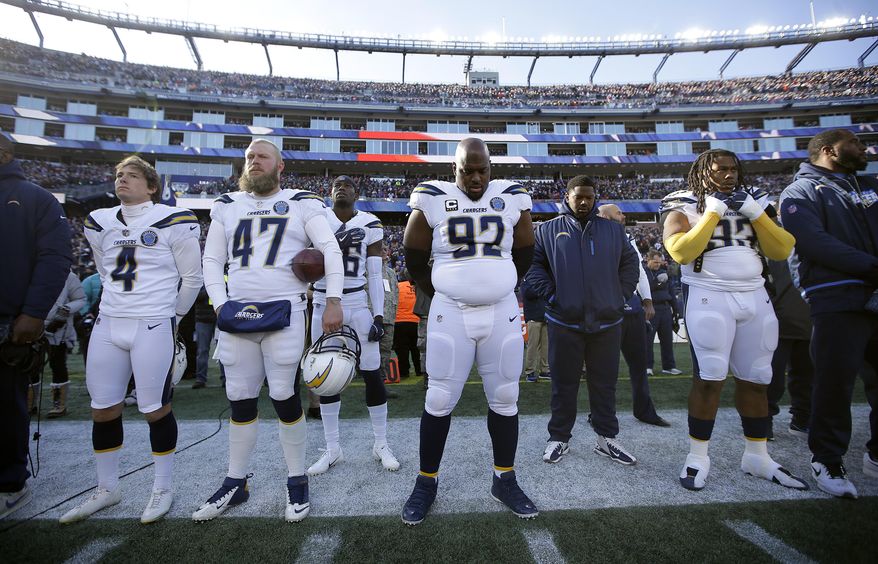 Los Angeles Chargers players, including defensive tackle Brandon Mebane (92), stand during the national anthem before an NFL divisional playoff football game against the New England Patriots, Sunday, Jan. 13, 2019, in Foxborough, Mass. (AP Photo/Steven Senne)