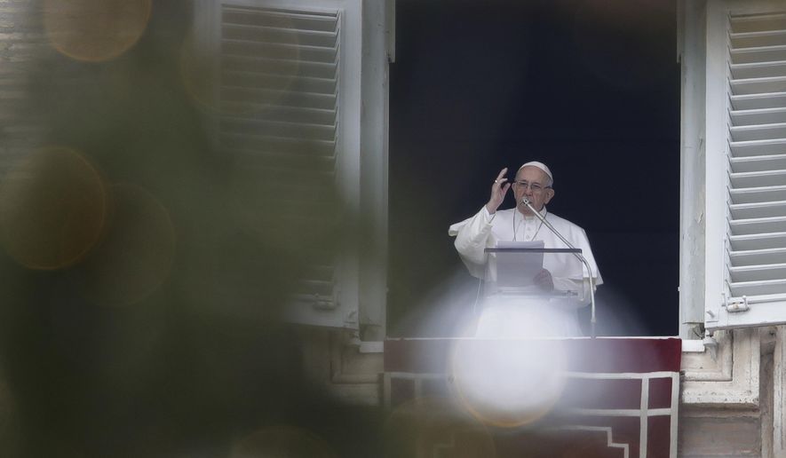 Framed by a Christmas tree, Pope Francis blesses the crowd as he recites the Angelus noon prayer from the window of his studio overlooking St.Peter's Square, at the Vatican, Sunday, Jan. 13, 2019. (AP Photo/Alessandra Tarantino)