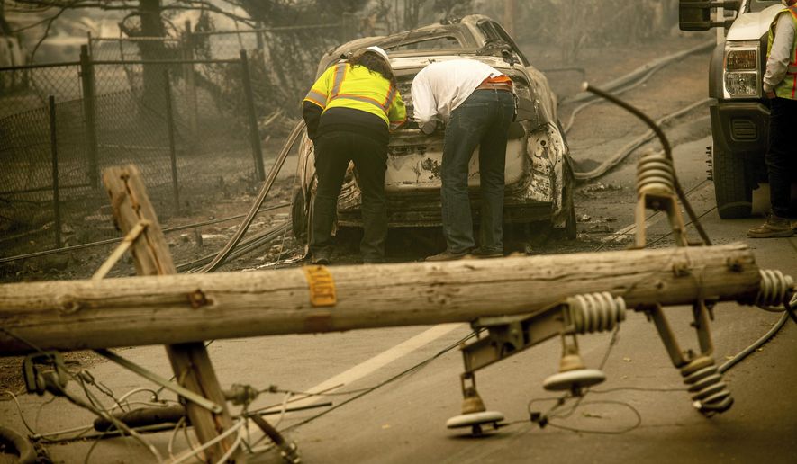 FILE - In this Nov. 10, 2018 file photo, with a downed power utility pole in the foreground, Eric England, right, searches through a friend&#39;s vehicle after the wildfire burned through Paradise, Calif. Facing potentially colossal liabilities over deadly California wildfires, PG&amp;amp;E will file for bankruptcy protection. The announcement Monday, Jan. 14, 2019, follows the resignation of the power company’s chief executive. (AP Photo/Noah Berger, File)