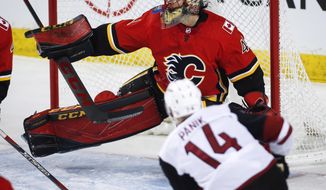 Arizona Coyotes&#39; Richard Panik, right, of the Czech Republic, has his shot deflected by Calgary Flames goalie Mike Smith during the first period of an NHL hockey game, Sunday, Jan. 13, 2019, in Calgary, Alberta. (Jeff McIntosh/The Canadian Press via AP)