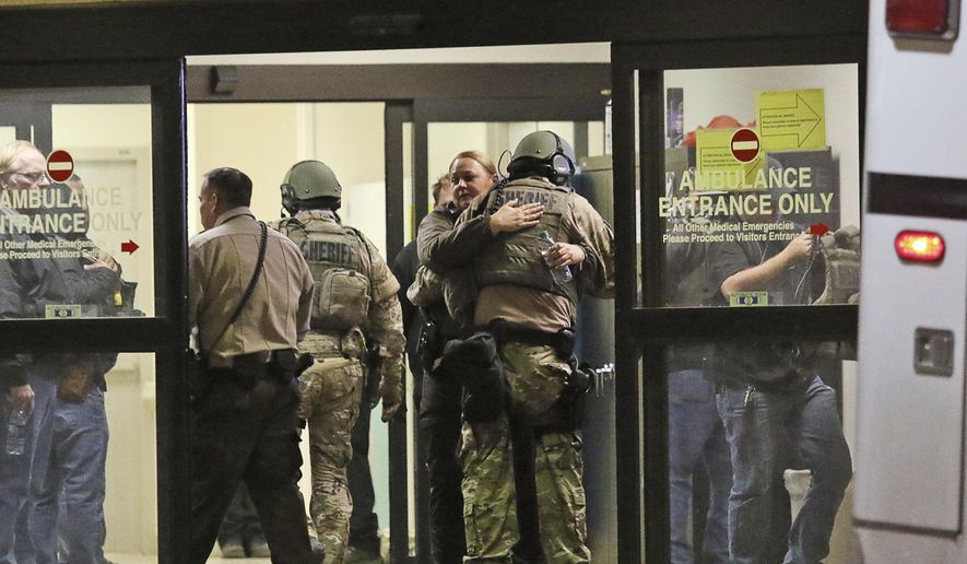Ector County Sheriff deputies hug in the ambulance entrance at Medical Center Hospital after three sheriff's deputies were shot in the line of duty, according to the Odessa American, late Monday, Jan. 14, 2019, in North Odessa, Texas. (Jacob Ford/Odessa American via AP)