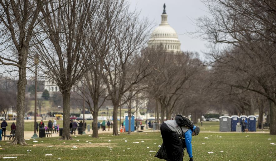 In this Dec. 25, 2018, file photo, the Capitol building is visible as a man picks up garbage during a partial government shutdown on the National Mall in Washington. (AP Photo/Andrew Harnik, File)