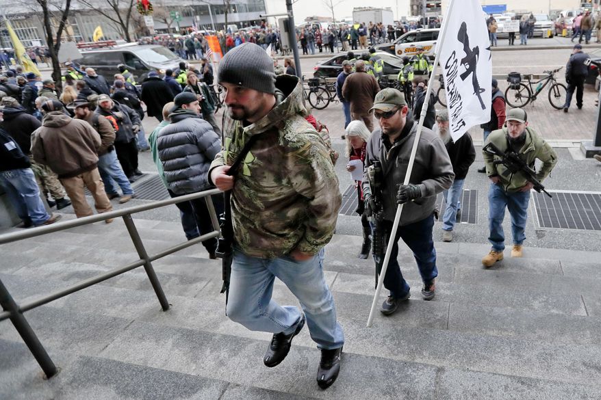 Protestors carrying rifles walk up the steps for a rally at the City County building on Monday, Jan. 7, 2019, in Pittsburgh. The protesters, many openly carrying guns, gathered in downtown Pittsburgh to rally against the city council's proposed restrictions and banning of semi-automatic rifles, certain ammunition and firearms accessories within city limits. (AP Photo/Keith Srakocic)