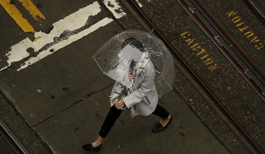 A woman walks in the rain while crossing an intersection in San Francisco, Wednesday, Jan. 16, 2019. A series of storms dropped rain up and down the state and snow in mountain regions this week, but the latest storm could be the strongest that Northern California has seen so far this year. (AP Photo/Jeff Chiu)