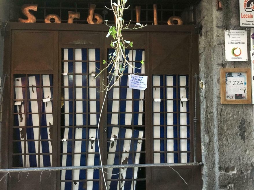 A view of the entrance to the historic Sorbillo pizzeria, in the historic center of Naples, where a bomb was detonated in the early hours of Wednesday, Jan. 16, 2019, damaging the eatery’s metal grating. The Italian news agency ANSA said eight bombs have targeted businesses in the Naples area in recent days. (Cesare Abbate/ANSA via AP)