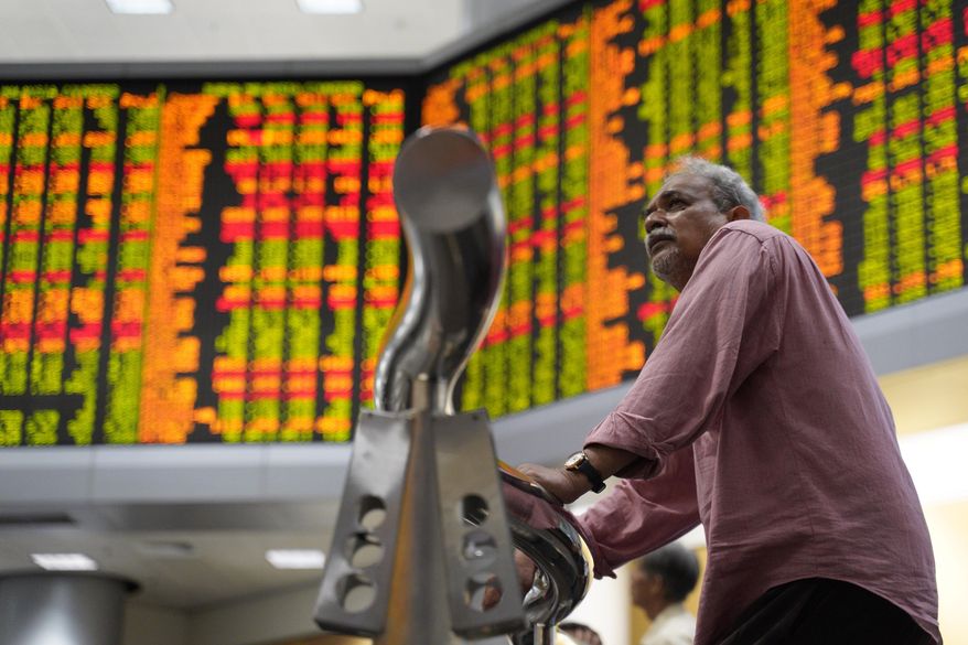 A visitor stands in front of stock trading boards at a private stock market gallery in Kuala Lumpur, Malaysia, Thursday, Jan. 17, 2019. Asian shares were mostly higher Thursday after strong earnings reports lifted indexes on Wall Street. (AP Photo/Yam G-Jun)