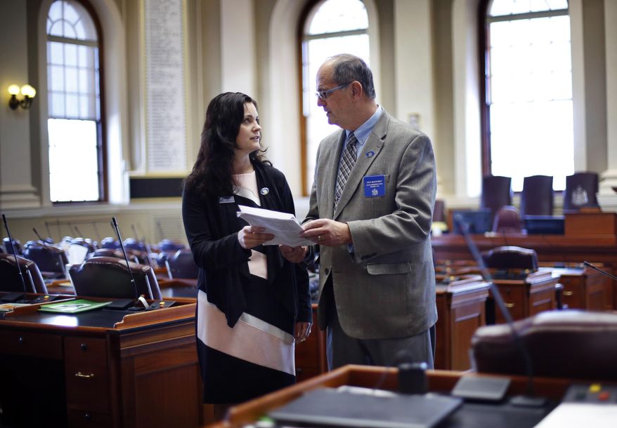 In this Thursday, Jan. 17, 2019 photo, Republican state Reps. Amy Arata and her father Richard Bradstreet discuss legislation in the House Chamber at the State House in Augusta, Maine. State records compiled by Maine's legislative library suggest they're the first father and daughter to serve as legislators together in Maine history. But they’re not the first pair nationwide. (AP Photo/Robert F. Bukaty)