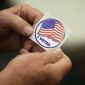 In this May 8, 2018, file photo, a person holds a sticker after placing his vote at the Durham County Library North Regional in Durham, N.C. (AP Photo/Gerry Broome, File)