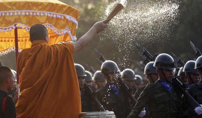 A Buddhist monk splashes holy water to Thai soldiers during the Royal Thai Armed Forces Day ceremony at a military base in Bangkok, Thailand, Friday, Jan. 18, 2019. (AP Photo/Sakchai Lalit)