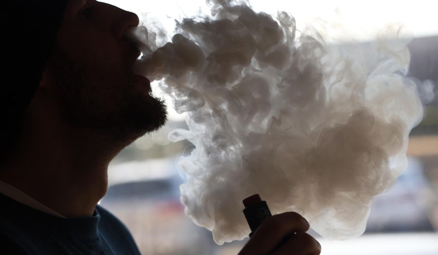 Richmonder Coleman Wheeler emits a cloud of smoke from a vape pipe at a local vape shop in Richmond, Va., Friday, Jan. 18, 2019. Tobacco-friendly Virginia is preparing to raise the age limit on buying traditional and electric cigarettes from 18 to 21. (AP Photo/Steve Helber)