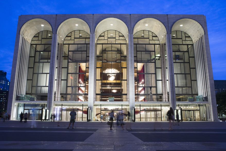 FILE - In this Aug. 1, 2014, file photo, pedestrians make their way in front of the Metropolitan Opera house at New York's Lincoln Center. The Metropolitan Opera says it is offering free tickets to people with government IDs from Saturday through the end of the month. A pair of tickets per performance can be reserved in advance by telephone or in person at the Met box office. (AP Poto/John Minchillo, File)