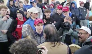 A teenager wearing a &quot;Make America Great Again&quot; hat, center left, stands in front of an elderly Native American singing and playing a drum in Washington, Friday, Jan. 18, 2019. The Roman Catholic Diocese of Covington in Kentucky is looking into this and other videos from a rally in Washington. (Survival Media Agency via AP) **FILE**