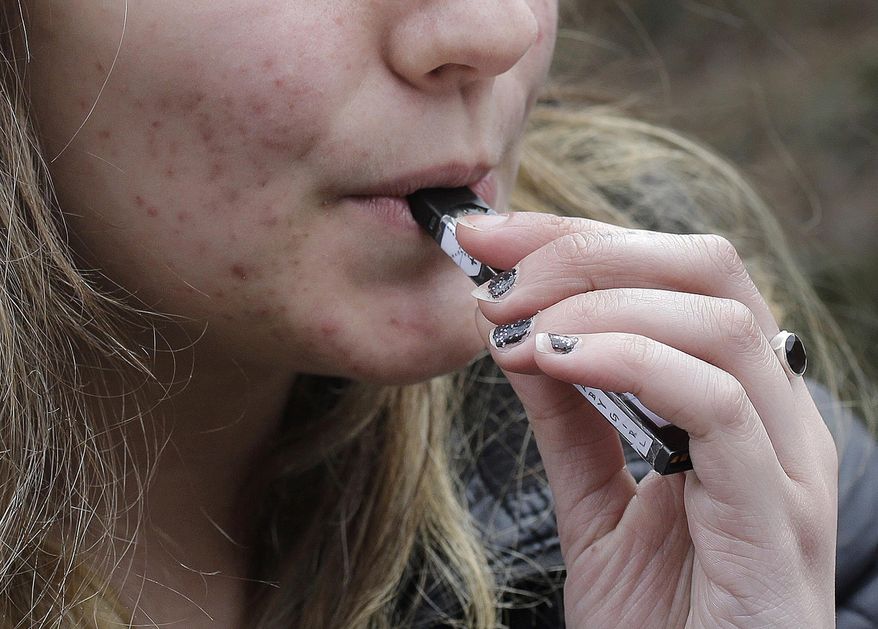 FILE - In this April 11, 2018 file photo, a high school student uses a vaping device near a school campus in Cambridge, Mass. Though education surveys show vaping use is down among Idaho high school students, health officials are concerned about vaping's rising popularity among teens nationwide. According to the National Institute of Drug Abuse, vaporized nicotine saw a dramatic uptick from 2017 to 2018 nationwide. (AP Photo/Steven Senne, File)