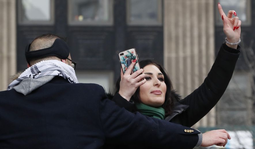 Political activist Laura Loomer, right, films herself on her smartphone as she is escorted off the stage after interrupting Women&#x27;s March NYC director Agunda Okeyo at a rally in Lower Manhattan, Saturday, Jan. 19, 2019, in New York. (AP Photo/Kathy Willens) ** FILE **