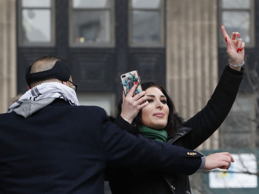 Political activist Laura Loomer, right, films herself on her smartphone as she is escorted off the stage after interrupting Women&#39;s March NYC director Agunda Okeyo at a rally in Lower Manhattan, Saturday, Jan. 19, 2019, in New York. (AP Photo/Kathy Willens) ** FILE **