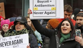 Political activist Laura Loomer, right, holds a sign across the street from a rally organized by Women&#39;s March NYC after she barged onto the stage interrupting Women&#39;s March NYC director Agunda Okeyo who was speaking during a rally in Lower Manhattan, Saturday, Jan. 19, 2019, in New York. Loomer was escorted off the stage after the incident. (AP Photo/Kathy Willens)