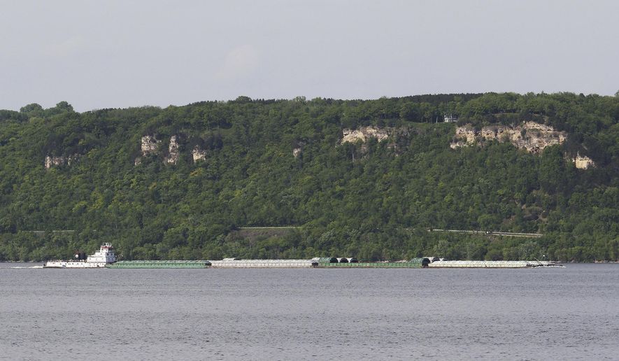 A towboat moves a line of barges on Lake Pepin as seen from near Lake City, Minn., on May 23, 2018. A plan to use sand and sediment removed from the Mississippi River to build several islands near the head of Lake Pepin is moving forward. (Andrew Krueger/Minnesota Public Radio via AP)