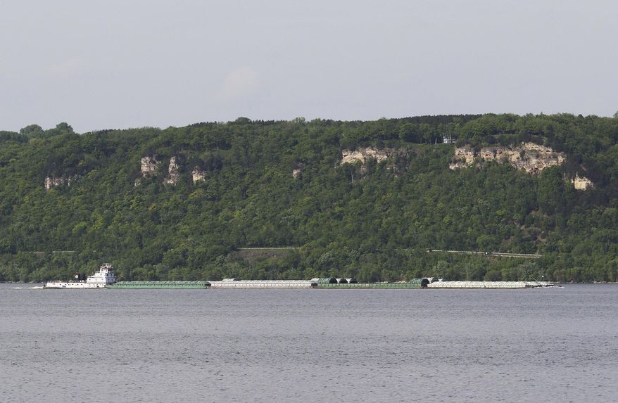 A towboat moves a line of barges on Lake Pepin as seen from near Lake City, Minn., on May 23, 2018. A plan to use sand and sediment removed from the Mississippi River to build several islands near the head of Lake Pepin is moving forward. (Andrew Krueger/Minnesota Public Radio via AP)