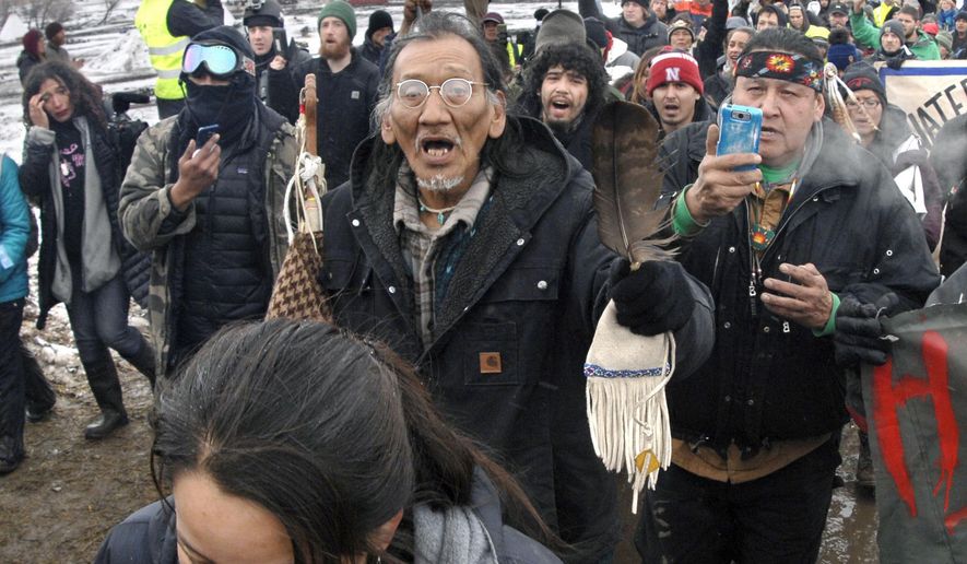 In this Feb. 22, 2017, file photo, a large crowd representing a majority of the remaining Dakota Access Pipeline protesters, including Nathan Phillips, center with glasses, march out of the Oceti Sakowin camp before the deadline set for evacuation of the camp near Cannon Ball, N.D. Phillips says he felt compelled to get between a group of black religious activists and largely white students with his ceremonial drum to defuse a potentially dangerous situation at a rally in Washington. (Mike McCleary/The Bismarck Tribune via AP, File)