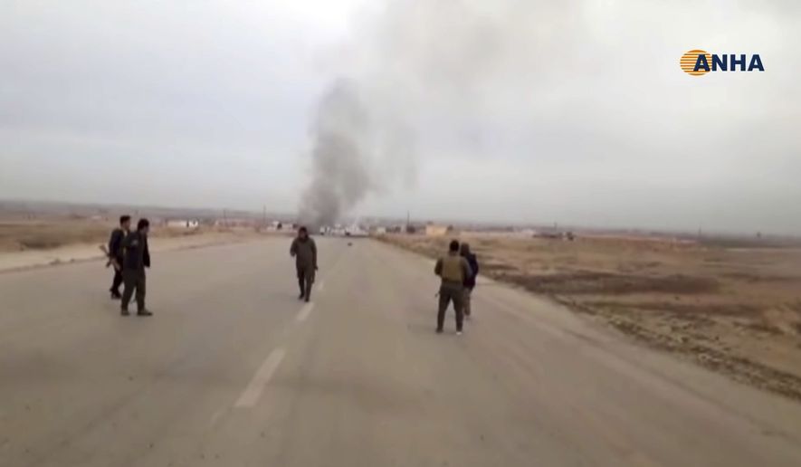 This frame grab from video provided by Hawar News, ANHA, the news agency for the semi-autonomous Kurdish areas in Syria, shows Kurdish fighters standing guard at the site of a suicide attack near the town of Shaddadeh, in Syria's northeastern province of Hassakeh, Syria, Monday, Jan. 21, 2019. The state news agency SANA and the Kurdish Hawar news agency, said that the blast was a suicide bombing that targeted a Syrian Kurdish checkpoint. (ANHA via AP)