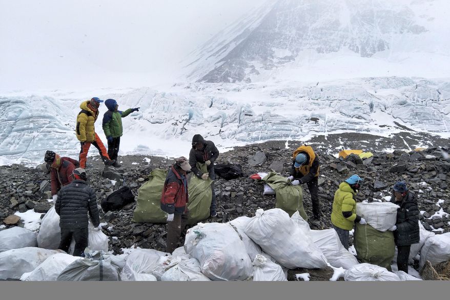 FILE - In this May 8, 2017, file photo released by Xinhua News Agency, people collect garbage at the north slope of the Mount Qomolangma in southwest China's Tibet Autonomous Region. China announced Monday, Jan. 21, 2019 that it plans to cut the number of climbers attempting to scale Mount Everest from the north by 1/3 this year as part of plans for a major cleanup on the world's highest peak. (Awang Zhaxi/Xinhua via AP)