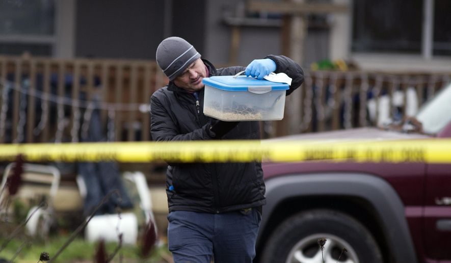 An investigator carries a box with a live snake, Monday, Jan. 21, 2019, outside a house where authorities say a man killed four members of his family, including his infant daughter, at the Canby, Oregon, home they shared, over the weekend. (Beth Nakamura/The Oregonian via AP)