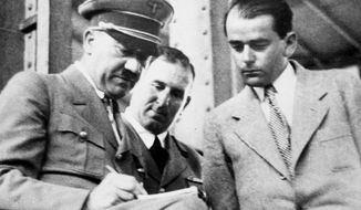 In this file photo dated Feb. 19, 1937, German Chancellor Adolf Hitler, left, discusses plans for building a convention hall at Nuremberg with Lord Mayor Willy Liebel, center, and Prof. Albert Speer, right, at Nuremberg, Germany. Hilde Schramm inherited several paintings collected by her father, Hitler’s chief architect and Armaments Minister Albert Speer, but she didn’t want them. Instead, Schramm sold them and used the money to start the Zurueckgeben foundation, translated to “return” or “give back”,  for which she is receiving an Obermayer German Jewish History Award on Monday, Jan. 21, 2019. (AP Photo, File)