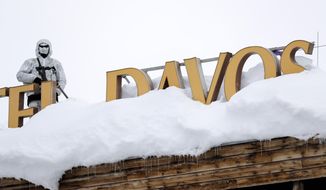 An armed Swiss police officer stands guard on the roof of a hotel near the congress center where the annual meeting of the World Economic Forum, WEF, take place in in Davos, Monday, Jan. 21, 2019. (AP Photo/Markus Schreiber)