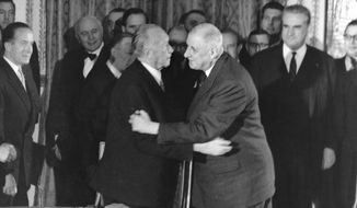 FILE - In this Jan. 22, 1963 file photo, German Chancellor Konrad Adenauer, centre left, hugs France President Charles de Gaulle after signing the Elysee friendship treaty in the Elysee palace in Paris, France. The leaders of France and Germany are poised to sign the Aachen accord Tuesday Jan. 22, 2019, renewing their friendship and pledging greater cooperation, exactly 56-years after their predecessors inked the Elysee Treaty that set the tone for the two countries’ future relations. (AP Photo/File)