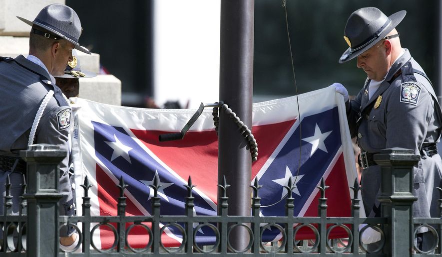 In this July 10, 2015, photo, members of an honor guard from the South Carolina Highway patrol lower the Confederate battle flag as it is removed from the Capitol grounds in Columbia, S.C. Confederate Relic Room Executive Director Allen Roberson said Tuesday, Jan. 22, 2019, museum staff put the flag into a $1,400 protective case on Nov. 26, ending a more than three-year saga. (AP Photo/John Bazemore) **FILE**