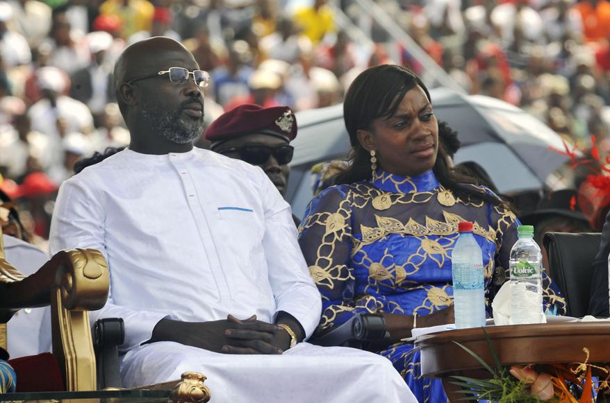 FILE - In this Jan. 22, 2018, file photo, Liberia's new President George Weah, left and his wife, Clar Weah, right, sit during his inauguration ceremony in Monrovia Liberia. Star footballer-turned-politician George Weah marks a year as Liberia's president on Tuesday Jan. 22, 2019, as many in the impoverished country debate whether he has begun to deliver on dramatic campaign promises. FIFA's 1995 player of the year in his inaugural speech vowed to give the West African nation's young population hope through job creation and a war on corruption, saying "Liberians will no longer be spectators in their own economy." (AP Photo/Abbas Dulleh, File)