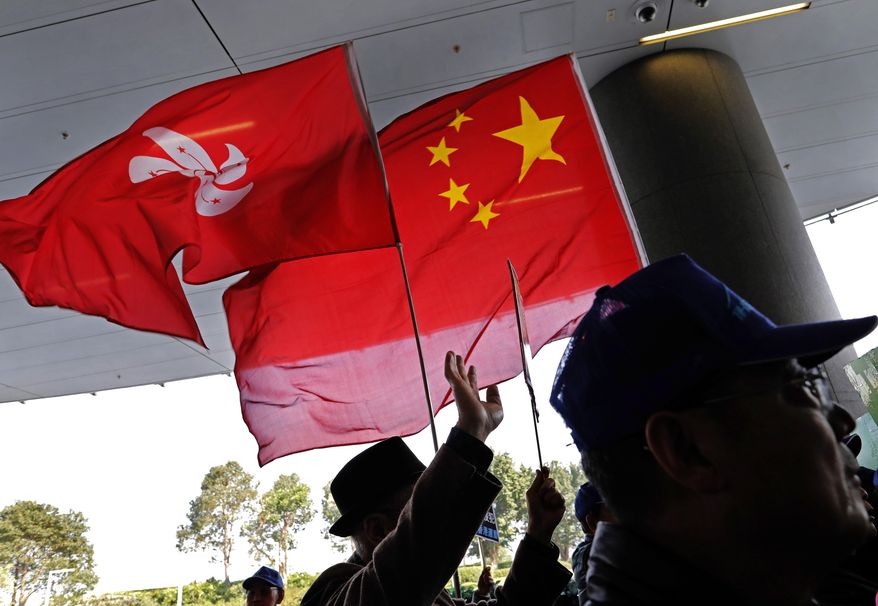 Pro-Beijing protesters raise the Chinese National flag and the Hong Kong flag during a protest outside Legislative building in Hong Kong, Wednesday, Jan. 23, 2019. Hong Kong’s legislature has taken up for consideration a bill that punishes anyone who "publicly and intentionally insults" the Chinese national anthem with up to three years in prison.(AP Photo/Vincent Yu)