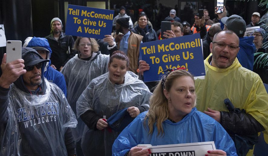 Furloughed government workers protest the government shutdown at the door of U.S. Sen. Mitch McConnell's office in Lexington, Ky., Wednesday, Jan 23, 2019. (AP Photo/Bryan Woolston)